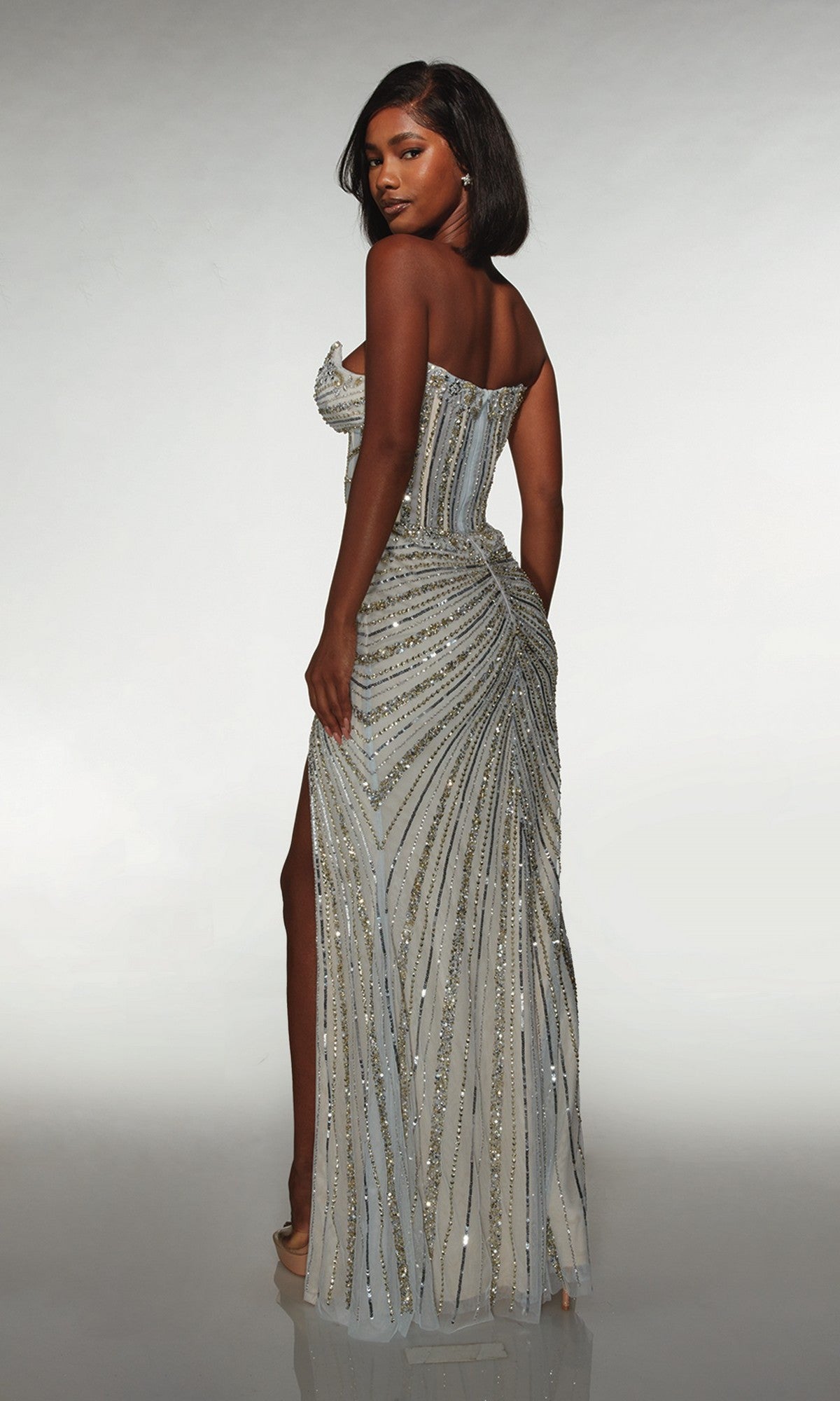 A woman models the Alyce 62167 long prom dress, a strapless gown with silver and gold sequins, intricate hand-beaded details, and a high-leg slit, set against a plain light background.